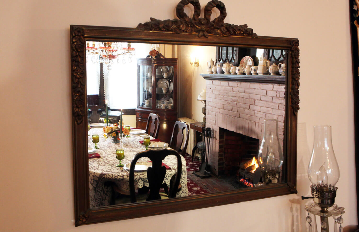 brown rectangular antique mirror reflects the Dining Room table and mauve fireplace