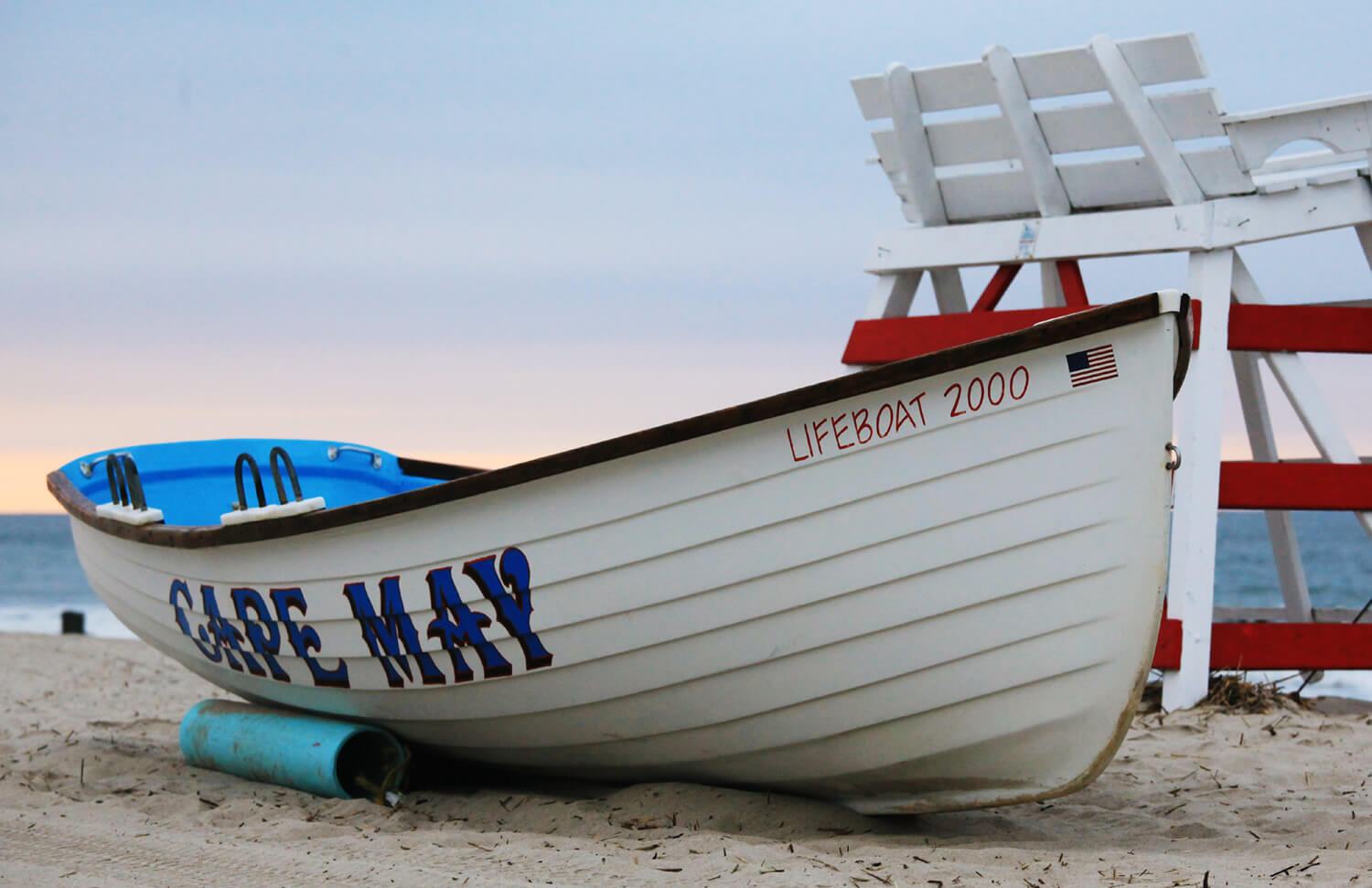 red and white lifeguard chair and white boat on the sandy beach