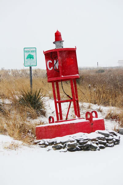 red buoy with white “CM” sitting on the brown and tan dunes