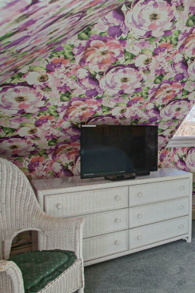 bed with white pedestal sink, white wicker mirror, and AC unit on wall